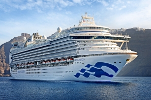 close up of the front of the Crown Princess cruise ship featuring the cliffs in the background and the deep blue sea
