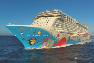 Image of the front of the Norwegian Breakaway cruise ship focusing on the vibrant base of the ship gliding through the calm sea 